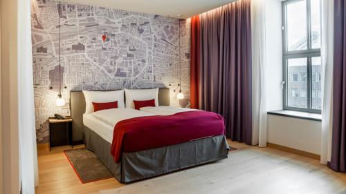 Eine Aufnahme eines Hotelzimmers auf dem ein Doppelbett zu sehen ist.